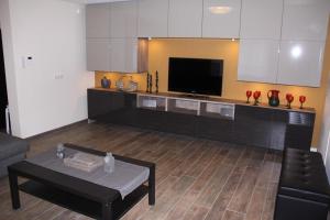 Il comprend une cuisine avec des placards blancs, une table et une télévision. dans l'établissement Villa Zonneweelde, au Coq