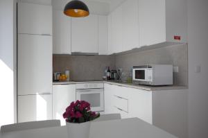 een keuken met witte apparatuur en een vaas met bloemen bij Double Suite by the Ocean in Paço de Arcos