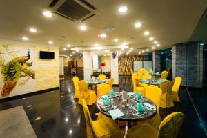 a restaurant with yellow chairs and tables and a television at AB Inn Hotel in Kulai