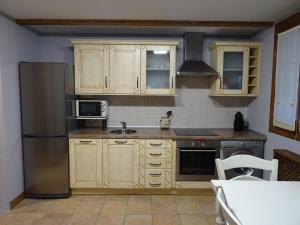 una cucina con armadi in legno e frigorifero in acciaio inossidabile di Apartamento Usuaia con jacuzzi a Lesaka