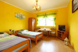 a yellow room with two beds and a television at Pokoje Stefania in Międzyzdroje
