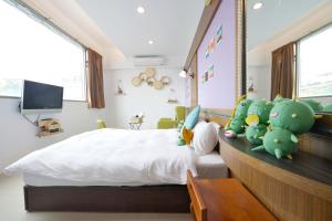 a bedroom with a bed with stuffed dinosaurs on it at PHSEA INN in Magong