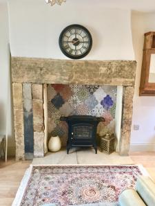 a living room with a fireplace with a clock on the wall at Eden's House in Hexham
