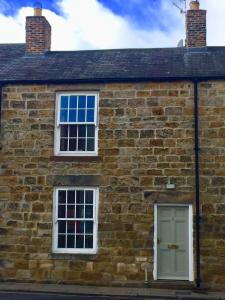 a brick building with a green door and two windows at Eden's House in Hexham