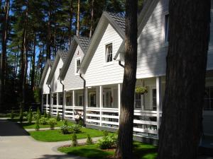 Casa blanca con porche y árboles en Domki letniskowe en Pobierowo