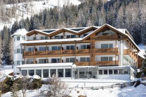 un gran edificio en la nieve frente a una montaña en Hotel Royal und Ferienhaus Annabel en Sesto