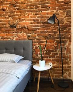 a bedroom with a bed and a lamp and a brick wall at VIP Apartment Ploscha Rynok in Lviv