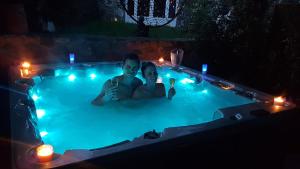 a man and woman sitting in a swimming pool at night at L'Attrape Reve in Saint-Vincent-de-Barrès