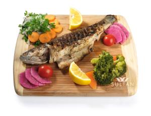 a plate of fish and vegetables on a cutting board at Sultan Hotel in Sivas