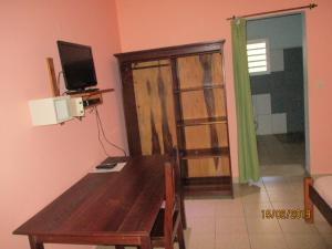 uma sala de jantar com uma mesa de madeira e uma televisão em Residence Kathyly em Antsiranana