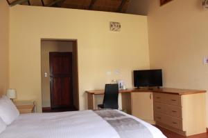 a bedroom with a bed and a desk with a television at Black Swan Guesthouse in Maseru