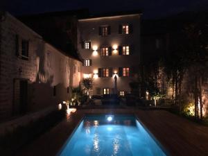 a swimming pool in front of a building at night at Palazzo Sbutega in Kotor