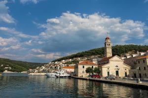 a town with a clock tower next to a body of water at House Olivia in Pučišća