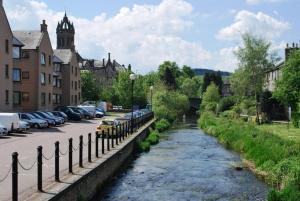 a river in a city with cars parked next to a street at 6 Northgate Vennel, Peebles in Peebles