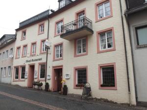 Un grand bâtiment blanc avec balcon se trouve dans une rue. dans l'établissement Hotel Haus Irsfeld, à Waxweiler