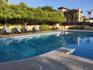 a swimming pool with chairs and a house at Sunny Garden Limassol Star - AEMAK-LEM in Limassol