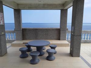 uma mesa e bancos numa varanda com o oceano em Sea Bay em Taitung City