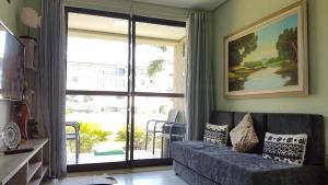 a living room with a couch and a large sliding glass door at Beach Class Eco Life Figueira in Porto De Galinhas