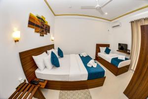 1 Schlafzimmer mit 2 Betten mit blauen und weißen Kissen in der Unterkunft Negombo New Queen's Palace in Negombo