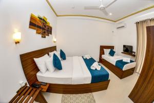 a bedroom with two beds with blue and white pillows at Negombo New Queen's Palace in Negombo