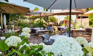 einen Garten mit Tischen, Stühlen und weißen Blumen in der Unterkunft Die Reichsstadt - Hotel Spa und Restaurant in Gengenbach