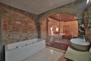 a bathroom with a tub and a sink and a bed at Çakıltaşı Evi Otel in Göreme