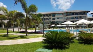 a resort with a pool and palm trees and a building at Beach Class Eco Life Figueira in Porto De Galinhas