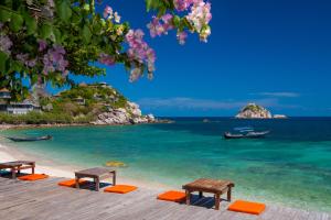 two benches sitting on a beach with the ocean at Coral View Resort in Ko Tao