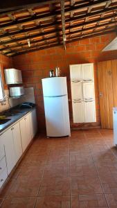 a kitchen with a white refrigerator and a brick wall at Chacara Dois Lagos - Mairinque in Mairinque
