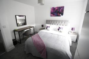 a white bedroom with a bed and a desk at Willow Serviced Apartments - 22 in Cardiff