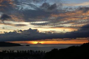 una puesta de sol sobre el océano con un cielo nublado en Prince Edouard Apartments & Resort SHA extra plus en Patong Beach