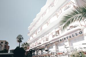 ヴァラッツェにあるHotel Cristalloのテーブルと椅子が備わる白い大きな建物