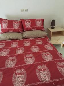 a bedroom with a bed with a red and white bedspread at Chouetterie in Saint-Dizier-Leyrenne