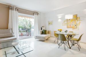 Athenian Riviera Beach Apartment في أثينا: غرفة معيشة بيضاء مع طاولة وكراسي زجاجية