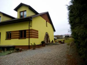 żółty dom z żwirowym podjazdem w obiekcie Pokoje na Wiejskiej w Nałęczowie