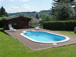 a swimming pool with two chairs on a wooden deck at BLUE PENSION s bazénem in Svoboda nad Úpou