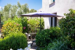 een patio met een parasol, stoelen en struiken bij Hotel le Mandala in Saint-Tropez