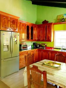 Seawind Cottage- Traditional St.Lucian Style في جزيرة جورس: مطبخ بدولاب خشبي وطاولة مع ثلاجة