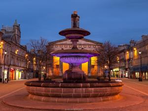 a fountain in the middle of a street at night at Distillery Apartment 1 in Elgin