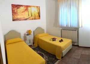 two beds in a room with yellow sheets at La Tuia in Quercegrossa