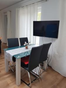 einen Esstisch mit Stühlen und einen Flachbild-TV in der Unterkunft 2 Raum Gartenwohnung am Spreewaldradweg in Cottbus in Cottbus