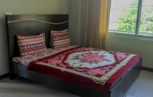 布爾班的住宿－Green Valley Bhurban Apartments，一间卧室配有一张带红色毯子和枕头的床。