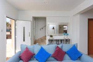 a living room with a blue couch with colorful pillows at SeaBreeze Villas by TrulyCyprus in Ayia Napa