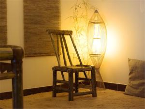 a wooden chair sitting in a room with a lamp at Ben Shu Jia Apartment Pazhou Branch in Guangzhou