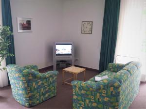 ein Wohnzimmer mit zwei Stühlen und einem Fernseher in der Unterkunft Eine schöne 3-Zimmer-Wohnung mit Ostsee-Zugang! in Juliusruh