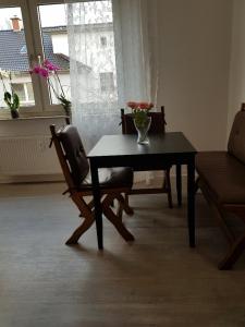 una mesa y una silla con un jarrón de flores. en Helle Ferienwohnung an der Rheinpromenade 50 qm, en Duisburg