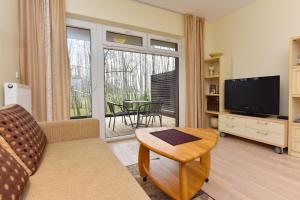 a living room with a couch and a tv and a table at Apartamentai Berzas in Palanga