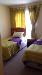 a bedroom with two beds and a window with curtains at Casas Amobladas y Equipadas Calama in Calama