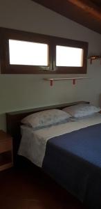 a bed in a bedroom with two windows at Appartamenti Villa Wanda in Palmi