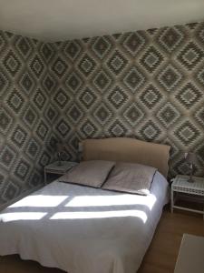- une chambre avec un lit et un mur avec un motif dans l'établissement La Ferme du Bois Quesnoy, à Saint-Pol-sur-Ternoise